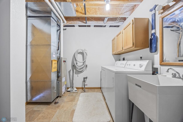 clothes washing area featuring washing machine and clothes dryer, heating unit, a sink, and cabinet space