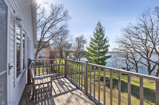 wooden deck with a water view and a lawn