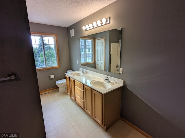 18061 96th Ave N, Maple Grove, MN 55311 - bathroom featuring a textured ceiling, baseboards, toilet, double vanity, and tile patterned floors