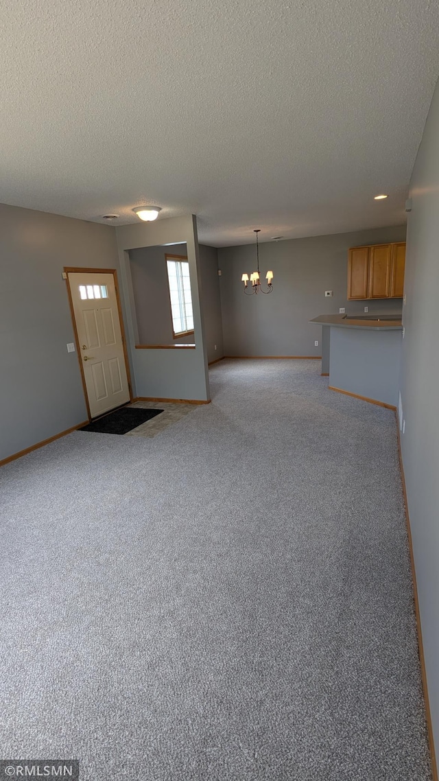 18061 96th Ave N, Maple Grove, MN 55311 - unfurnished living room featuring a chandelier, a textured ceiling, carpet, and baseboards