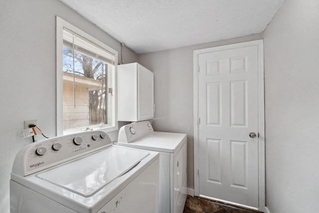 laundry area with washer and clothes dryer, a textured ceiling, and cabinet space