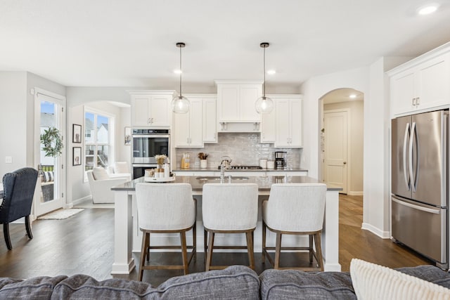 10914 23rd St NE, Saint Michael, MN 55376 - kitchen featuring appliances with stainless steel finishes, arched walkways, a kitchen breakfast bar, and recessed lighting