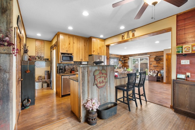 12 Oak Ave SE, Racine, MN 55967 - kitchen with stainless steel appliances, light wood-style flooring, a kitchen bar, ceiling fan, and dark stone counters