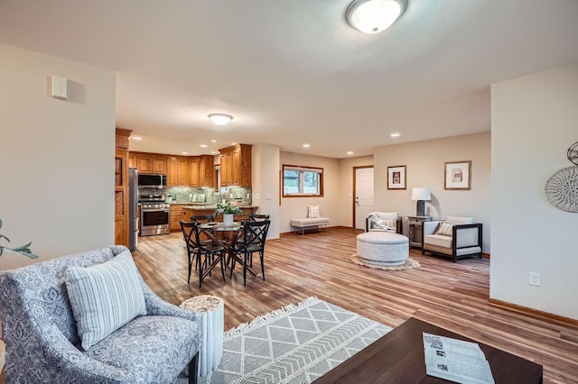 living area featuring recessed lighting, baseboards, and light wood finished floors