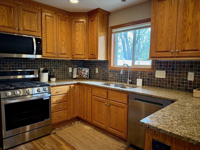 kitchen featuring a sink, decorative backsplash, brown cabinetry, and stainless steel appliances