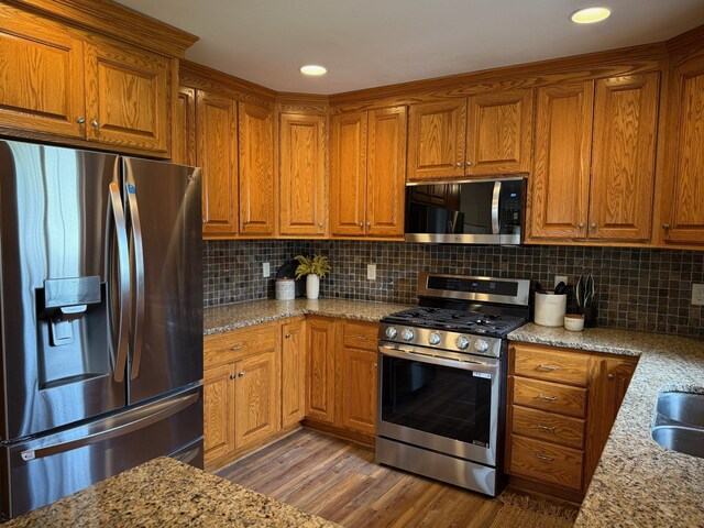 kitchen featuring light wood finished floors, brown cabinets, and stainless steel appliances