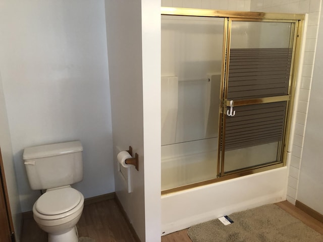 full bathroom featuring enclosed tub / shower combo, toilet, wood finished floors, and baseboards