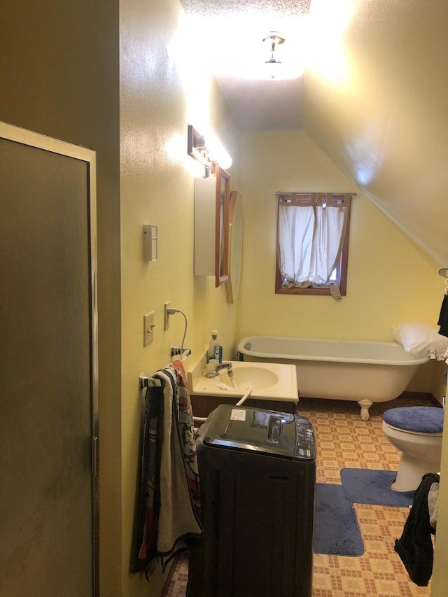 full bathroom featuring vaulted ceiling, washer and clothes dryer, a sink, a stall shower, and a freestanding bath