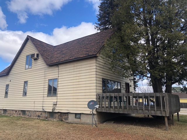 view of side of property featuring a wooden deck, a wall mounted air conditioner, and a shingled roof