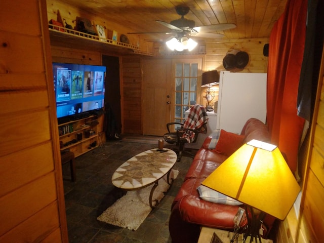 living area with wooden walls, wood ceiling, and a ceiling fan