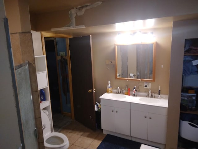 bathroom with toilet, double vanity, tile patterned floors, and a sink