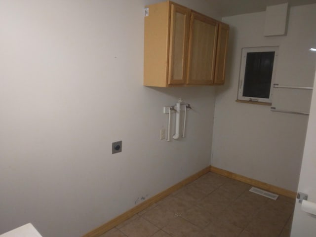 washroom featuring cabinet space, electric dryer hookup, baseboards, light tile patterned floors, and visible vents