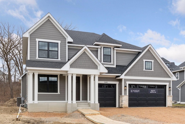 craftsman inspired home featuring dirt driveway, central air condition unit, covered porch, roof with shingles, and a garage