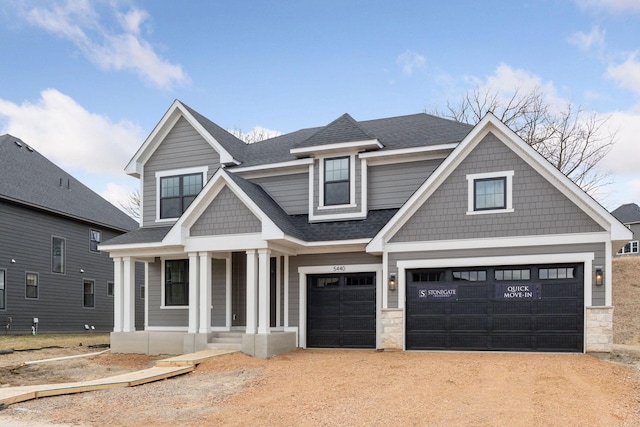 craftsman-style house featuring driveway, an attached garage, covered porch, and roof with shingles