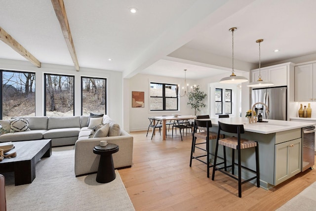 living area featuring light wood-type flooring, an inviting chandelier, beam ceiling, and recessed lighting