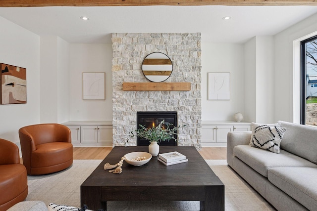 living room featuring recessed lighting, light wood-style flooring, and a stone fireplace
