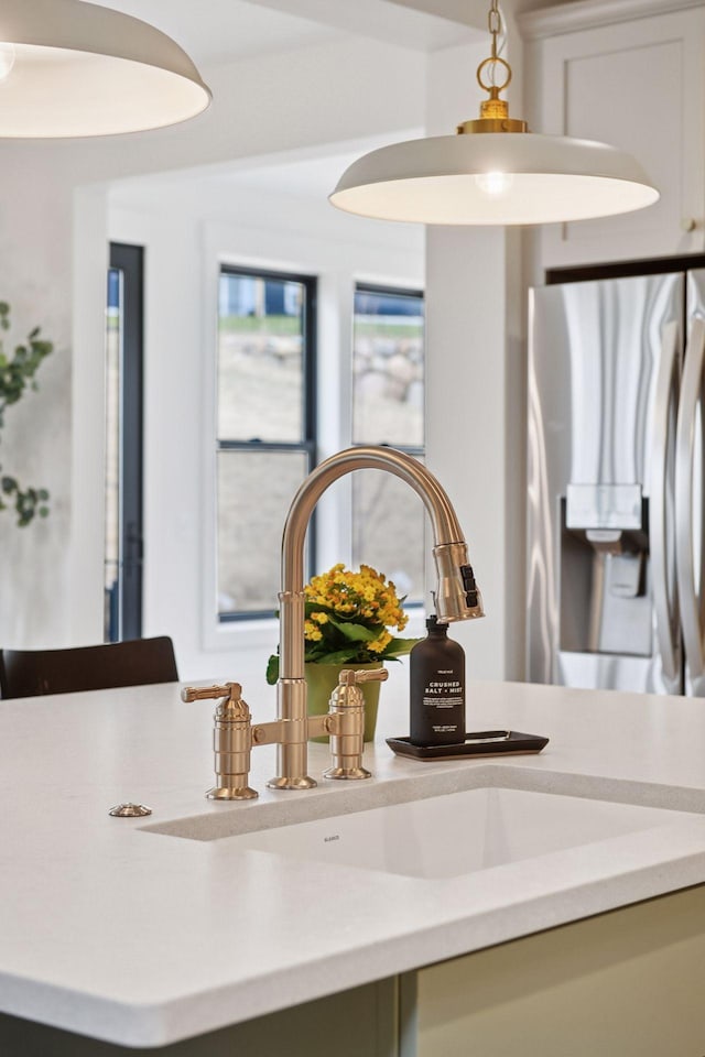 room details featuring stainless steel fridge with ice dispenser, a sink, and light countertops