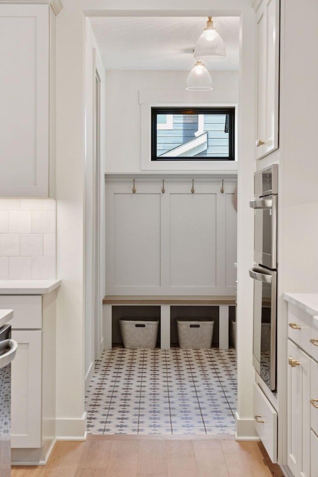 mudroom with a decorative wall and a wainscoted wall
