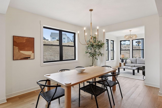 dining space with an inviting chandelier, light wood-style floors, and baseboards