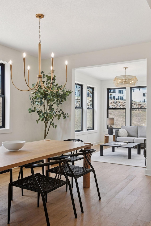 dining area with baseboards, an inviting chandelier, light wood finished floors, and a wealth of natural light