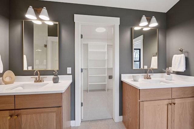 full bathroom with a walk in closet, two vanities, tile patterned flooring, and a sink