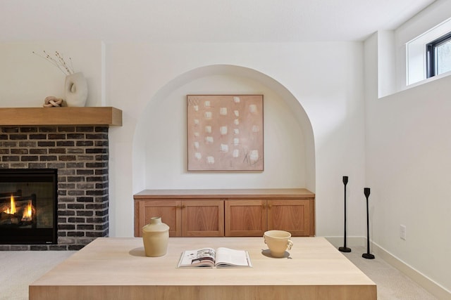 interior space featuring baseboards, a brick fireplace, and carpet floors