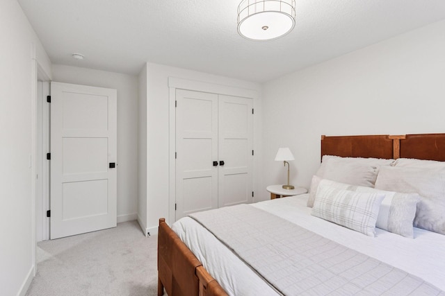 bedroom with baseboards, a closet, and light colored carpet