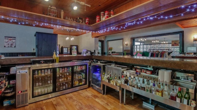 bar with wood ceiling, wood finished floors, a bar, and wine cooler