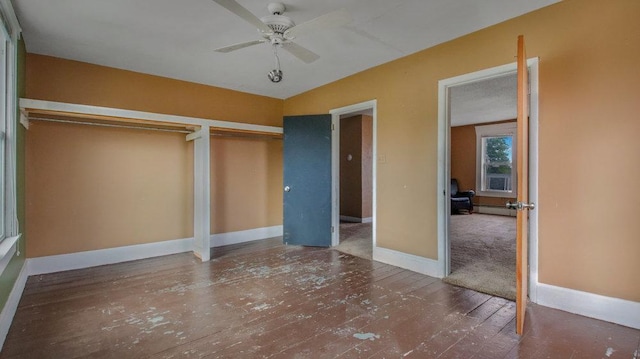 unfurnished bedroom with a baseboard heating unit, wood-type flooring, baseboards, and ceiling fan
