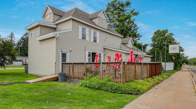 exterior space featuring a yard, a shingled roof, and a deck