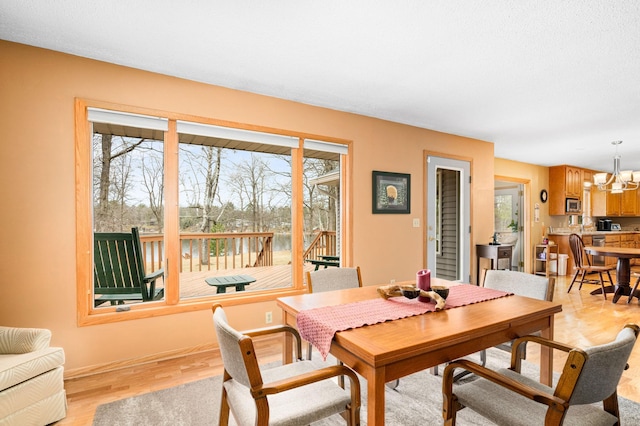 dining room featuring baseboards, a chandelier, and light wood-type flooring