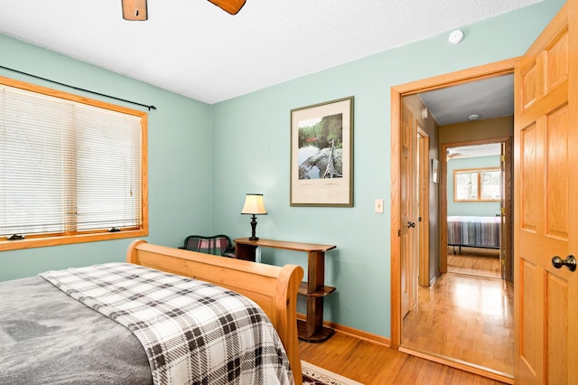 bedroom featuring light wood-style floors, baseboards, and ceiling fan