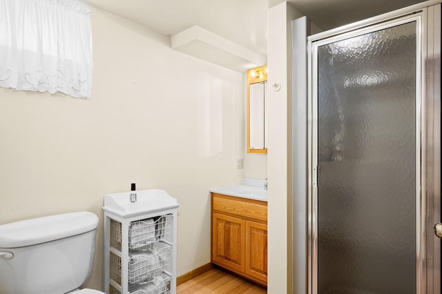 full bath featuring a shower stall, vanity, toilet, and wood finished floors