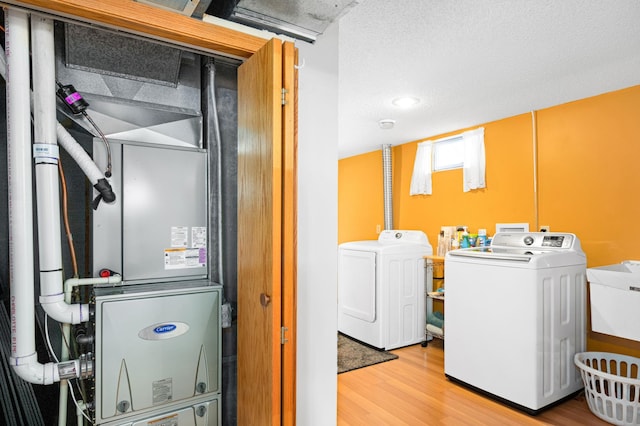 laundry area featuring washer and clothes dryer, a sink, wood finished floors, laundry area, and heating unit