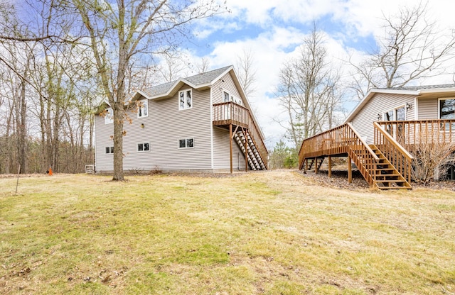 rear view of property with stairway, a deck, a shingled roof, and a lawn