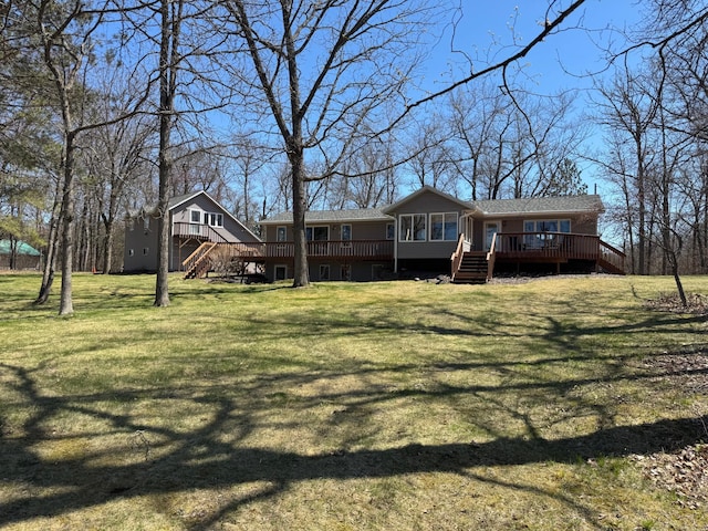rear view of property featuring a yard, stairs, and a wooden deck