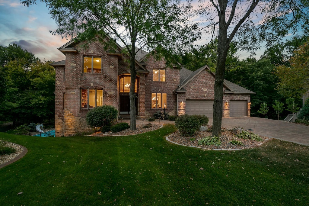 traditional home with an attached garage, brick siding, concrete driveway, and a front yard