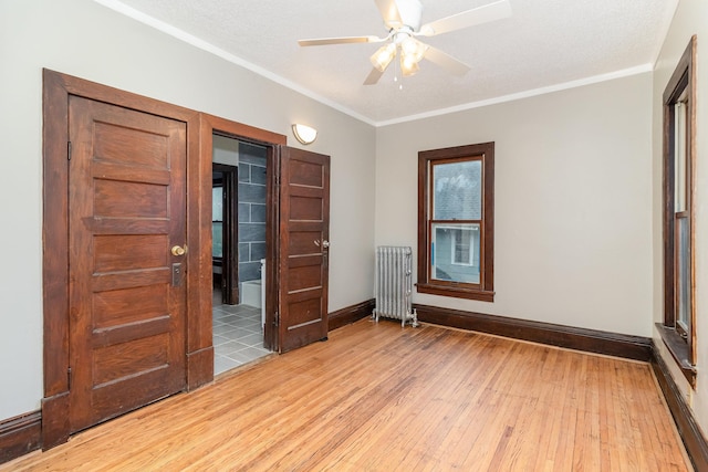 2807 17th Ave S, Minneapolis, MN 55407 - unfurnished room with radiator heating unit, light wood-type flooring, baseboards, a ceiling fan, and crown molding