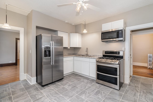 2807 17th Ave S, Minneapolis, MN 55407 - kitchen with stainless steel appliances, a sink, white cabinetry, ceiling fan, and radiator heating unit