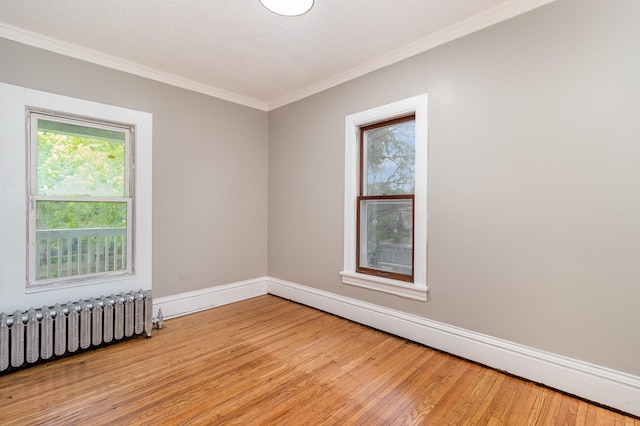 2807 17th Ave S, Minneapolis, MN 55407 - empty room with radiator heating unit, ornamental molding, light wood-type flooring, baseboards, and a baseboard heating unit