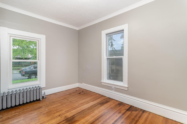 2807 17th Ave S, Minneapolis, MN 55407 - empty room with radiator, wood finished floors, crown molding, baseboards, and a textured ceiling