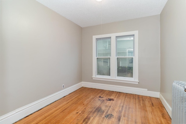 2807 17th Ave S, Minneapolis, MN 55407 - empty room with radiator, hardwood / wood-style flooring, baseboards, and a textured ceiling