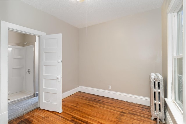 2807 17th Ave S, Minneapolis, MN 55407 - unfurnished bedroom featuring radiator, light wood-style flooring, baseboards, and a textured ceiling