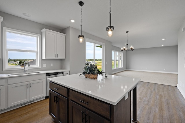 kitchen featuring a sink, a chandelier, dishwasher, light countertops, and white cabinets