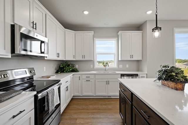 kitchen with white cabinets, stainless steel appliances, a sink, recessed lighting, and light countertops