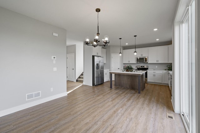 kitchen featuring stainless steel appliances, light wood-style flooring, visible vents, and a chandelier