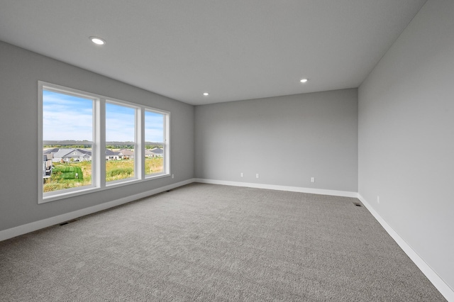 unfurnished room with carpet, baseboards, visible vents, and recessed lighting