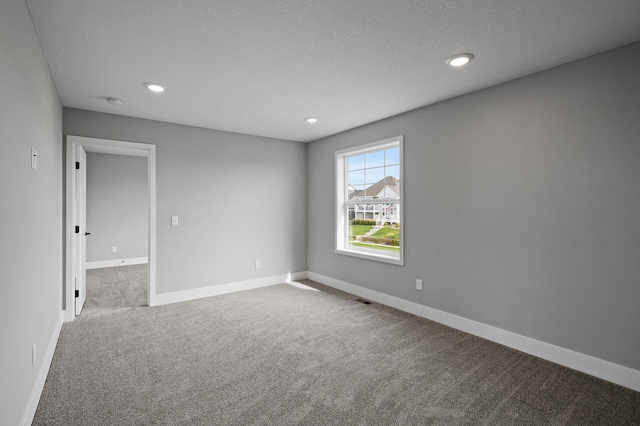 spare room with a textured ceiling, baseboards, carpet, and recessed lighting