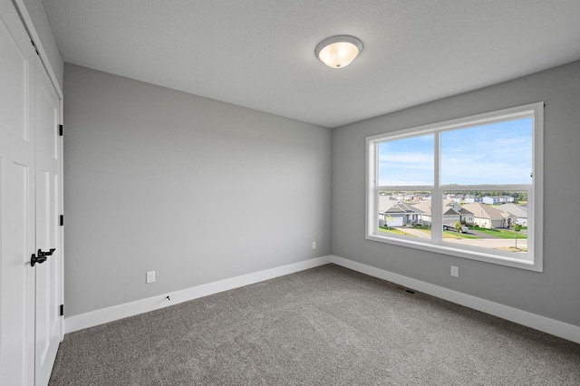 spare room with visible vents, baseboards, carpet flooring, and a residential view
