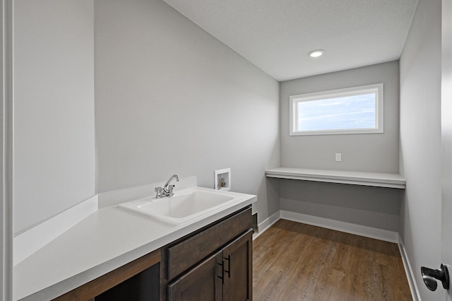 bathroom with baseboards, vanity, wood finished floors, and recessed lighting